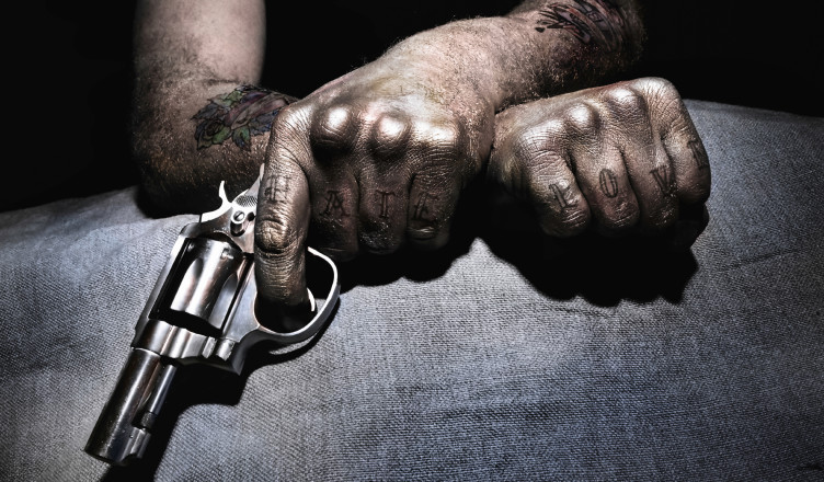 A tattooed member of gangs holding a gun.